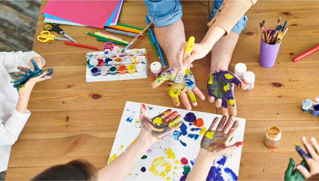 Children's hand painting session against the backdrop of a wooden table.