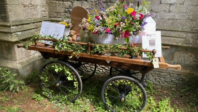 A funeral barrow with farewell messages and colourful flowers.