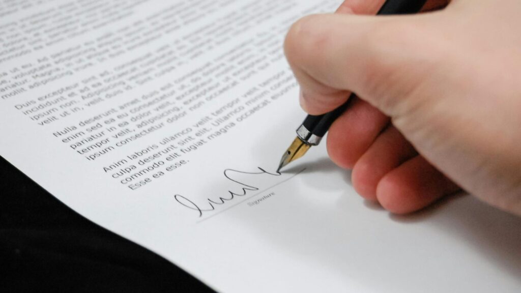 Hand using inkpen to sign a document 16 x 9.